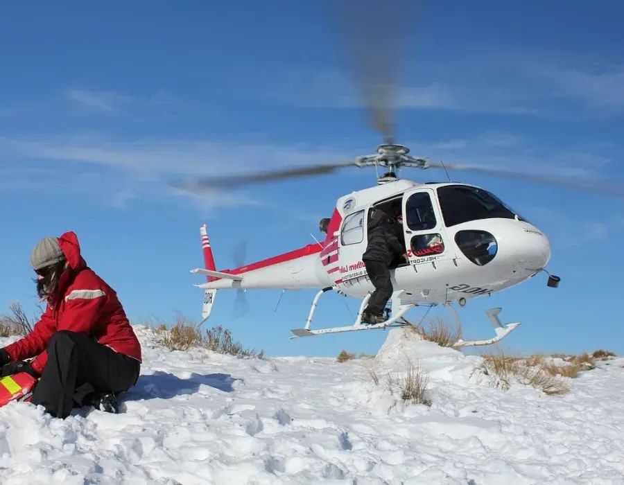 Flight nurse administering treatment in the field with helicopter in the background